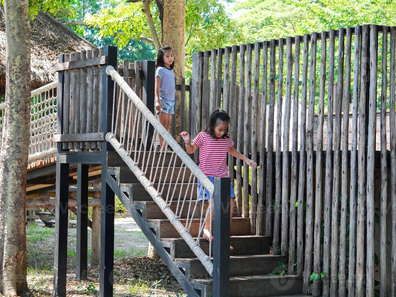 Kids play outdoors on a playground with modern slides, rope net bridges, climbing swings, climbers in summer. photo