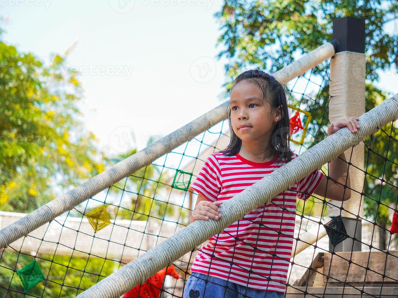 Kids play outdoors on a playground with modern slides, rope net bridges, climbing swings, climbers in summer. photo