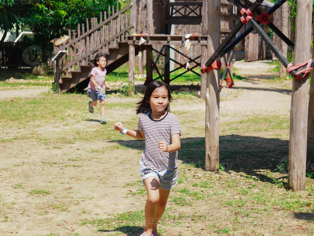 Kids play outdoors on a playground with modern slides, rope net bridges, climbing swings, climbers in summer. photo