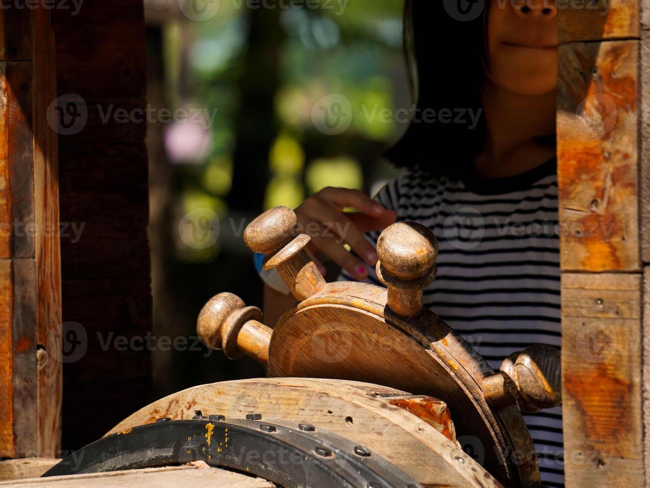 Children play outdoors on a wooden playground in a park. Happy girl playing with wooden train in playground during summer. photo