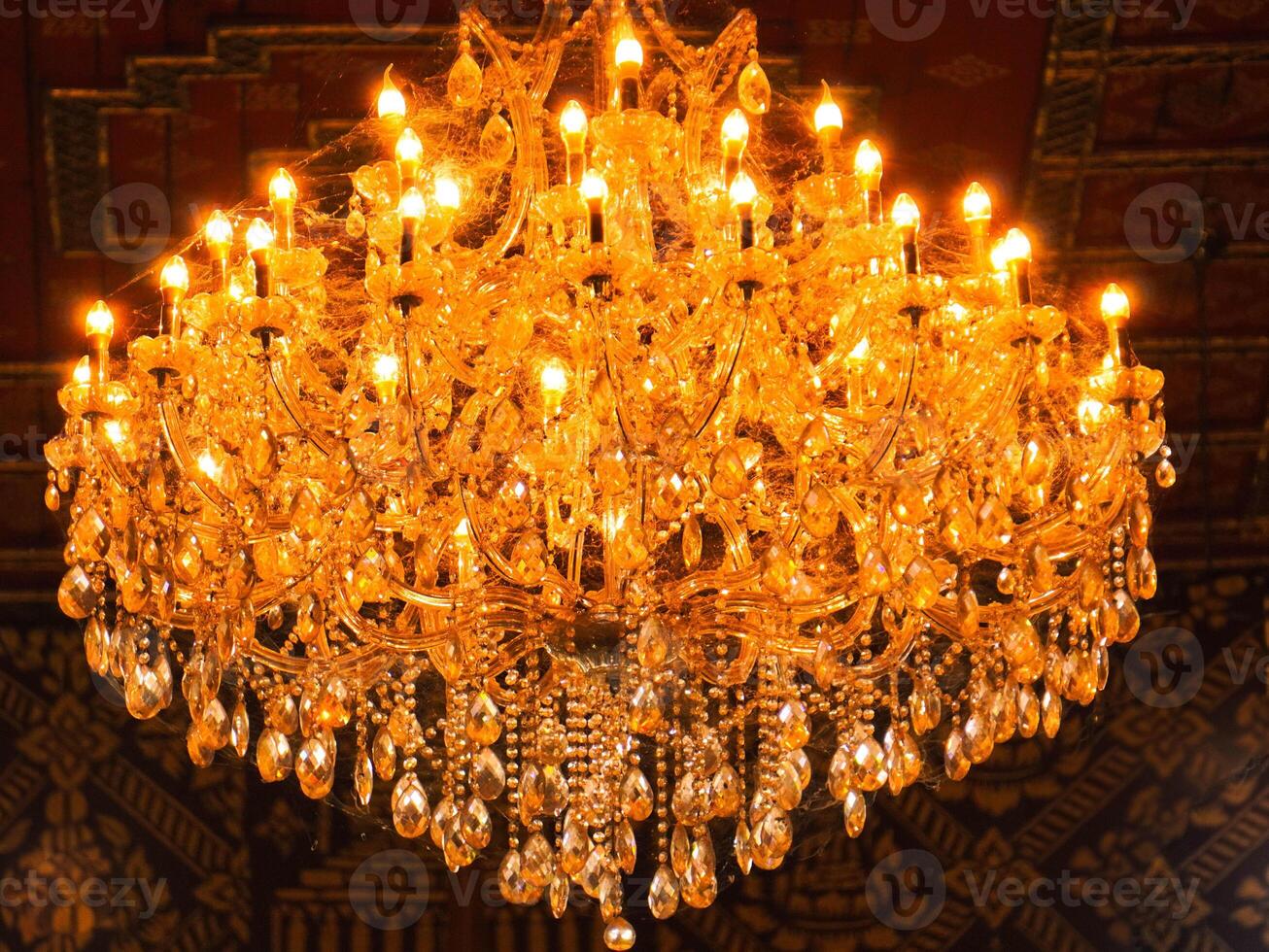 A grand gold chandelier hangs from the ornate ceilingeiling. photo