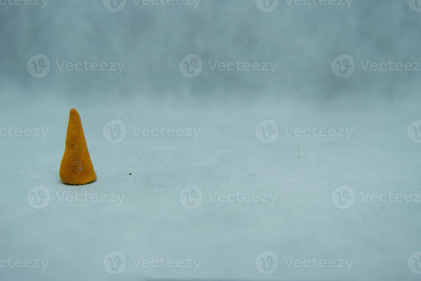 A small orange cone sitting on a white surface photo