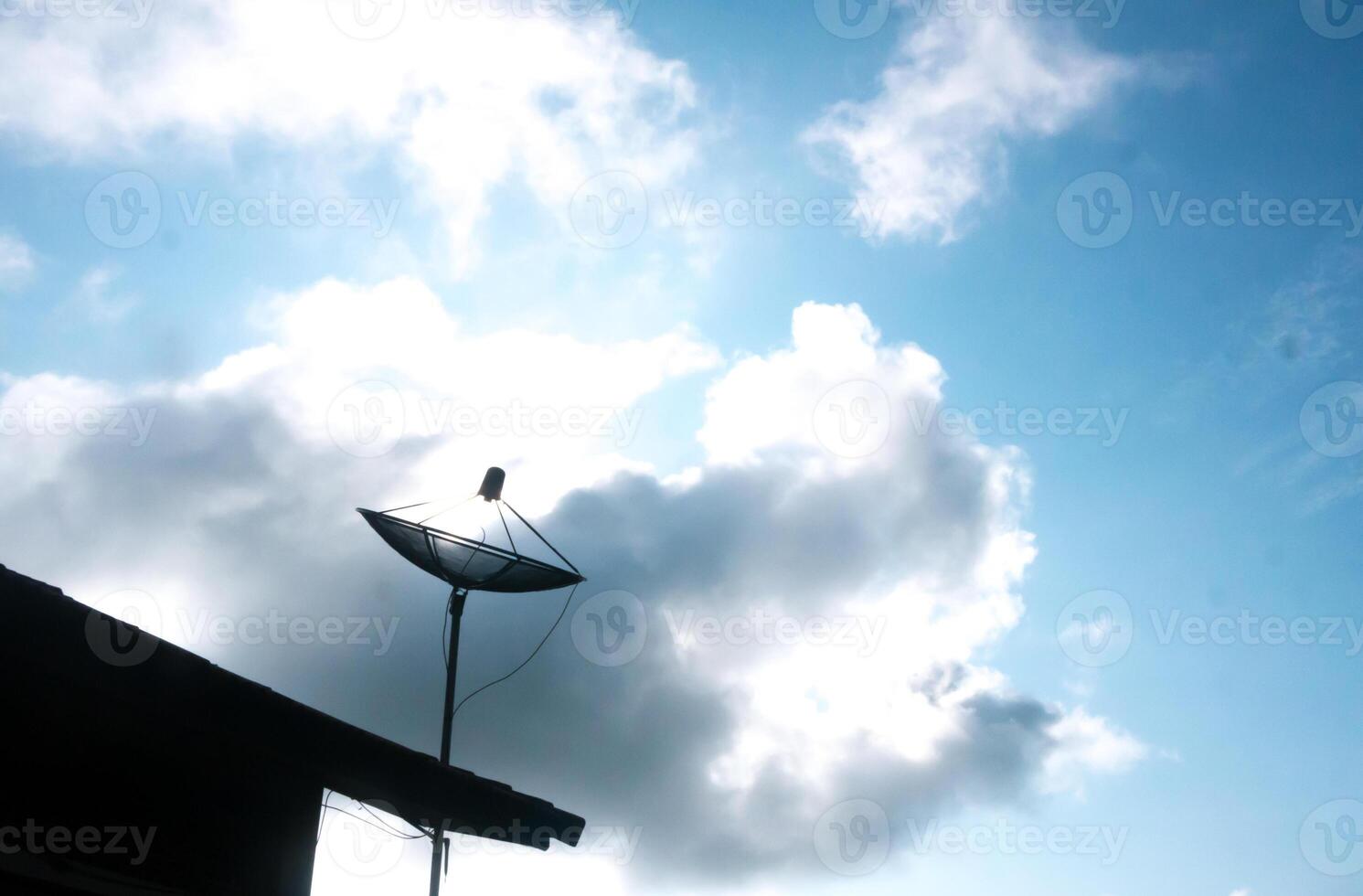 A satellite dish on a roof with a cloudy sky photo