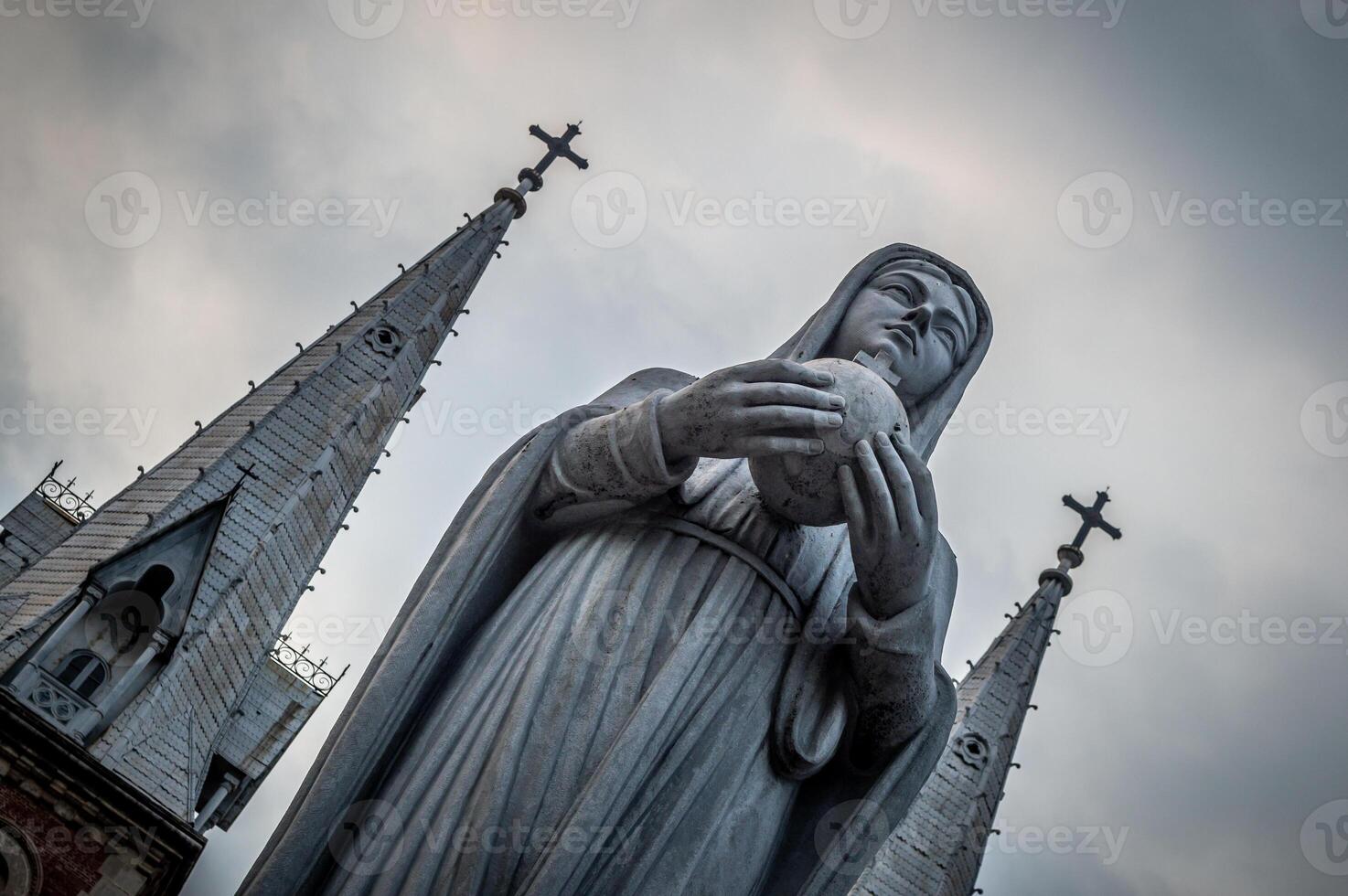 A statue of a nun holding a ball in front of a church photo