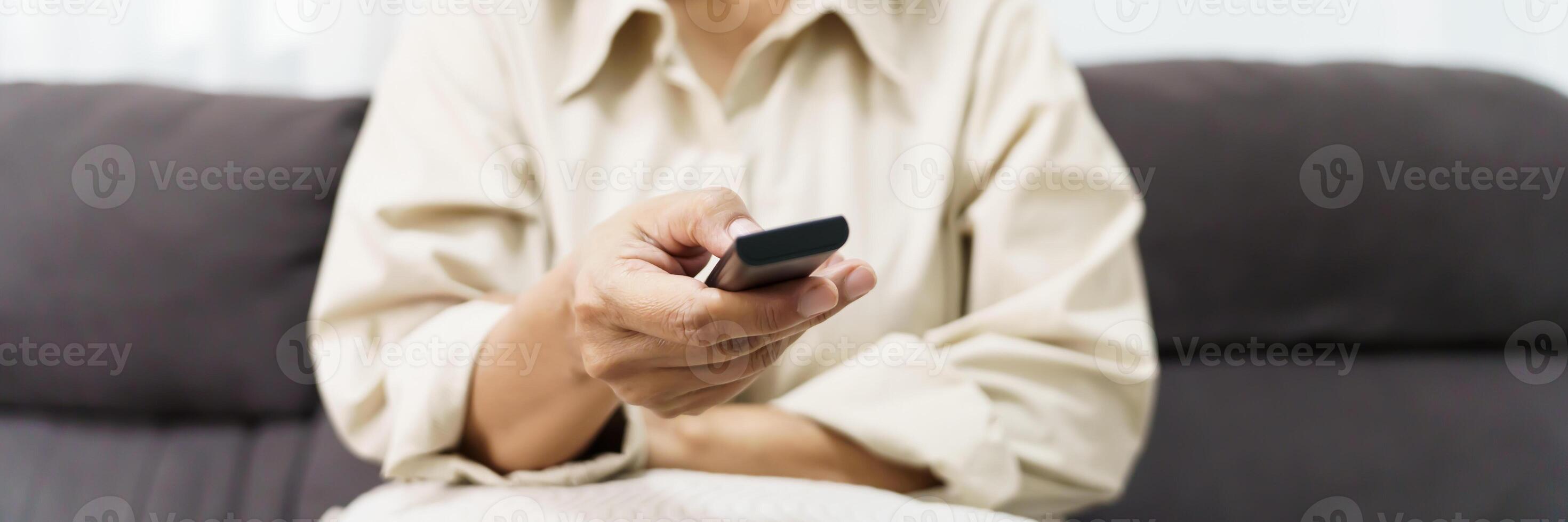 Elderly woman Watching smart TV and using remote controller Hand holding television audio remote control Middle age Asian woman movie Television series spending time at home photo