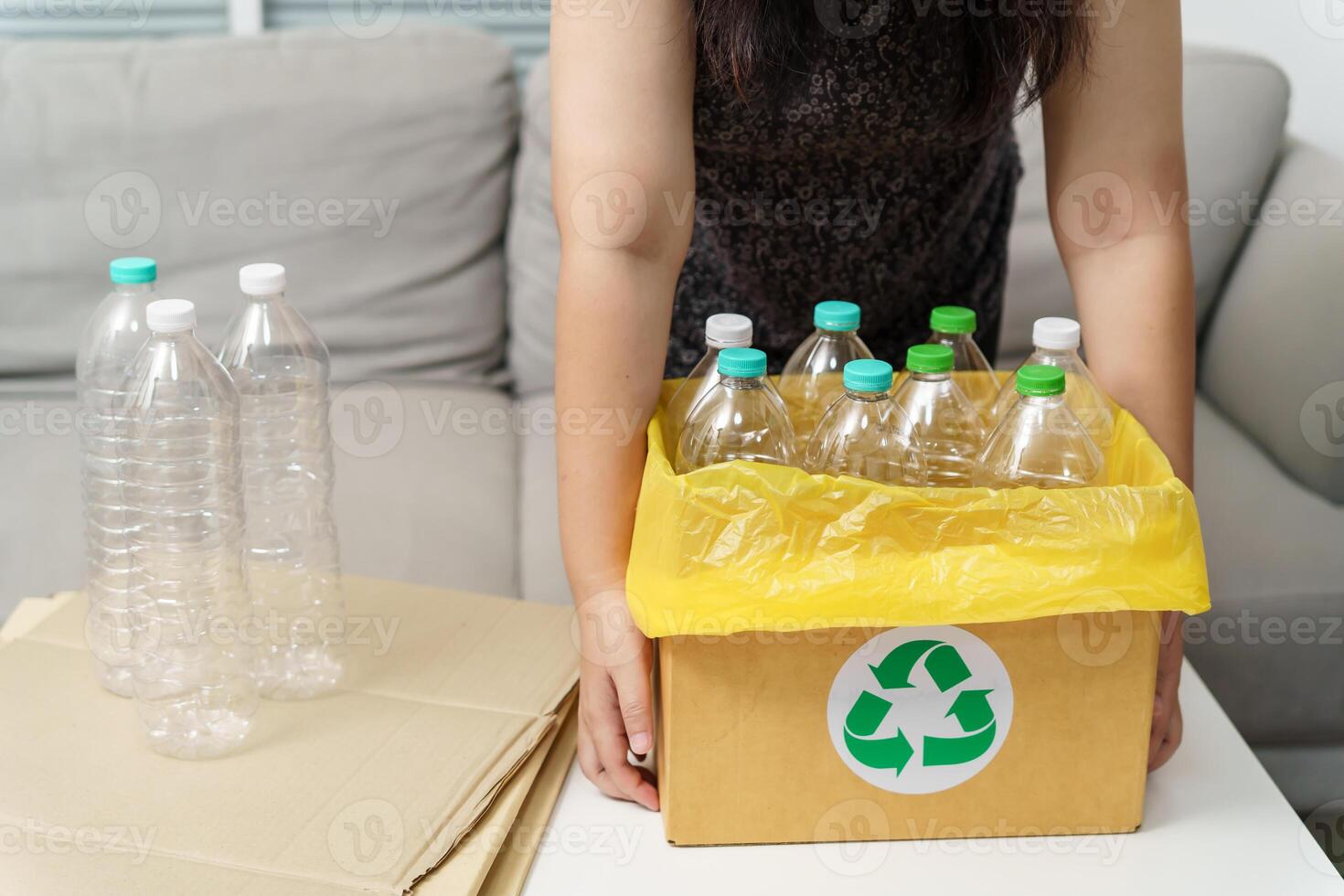 Home recycle eco green zero concept Woman throwing empty plastic bottle in recycling bin with yellow garbage bags at home. photo