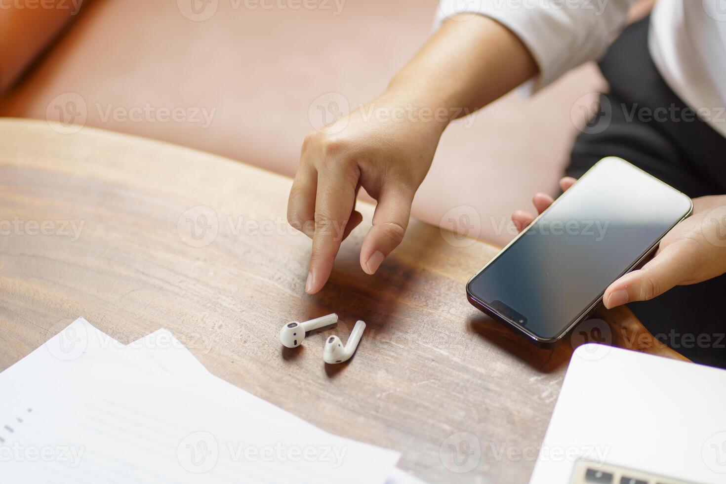 woman takes out wireless bluetooth headphones. earphones using smartphone photo