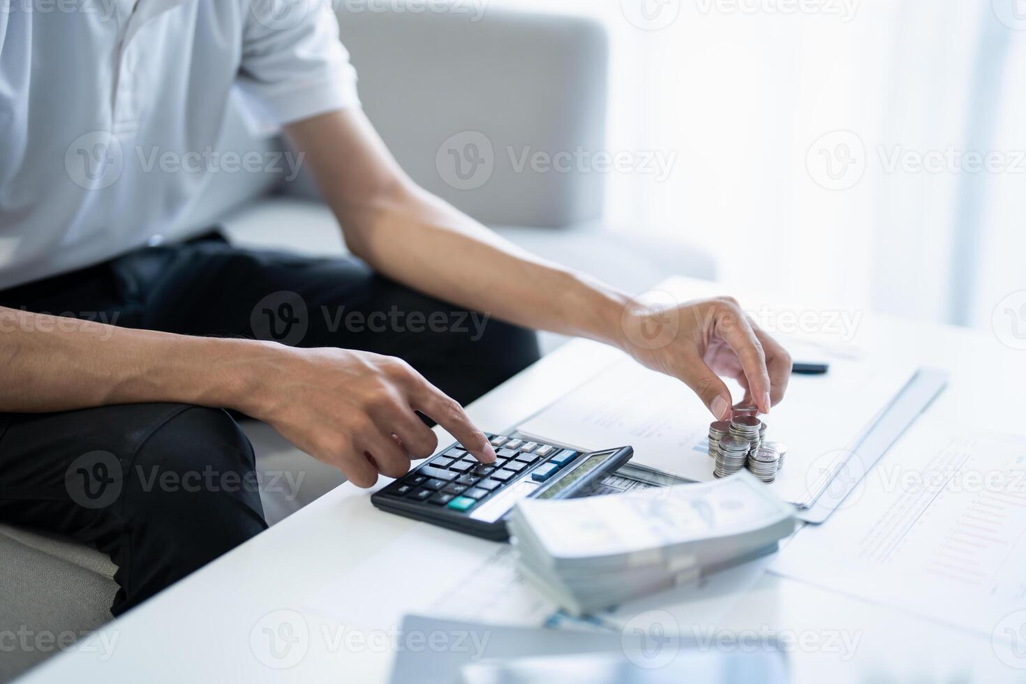 Saving money. Man calculate finances home pay bills taxes savings economy financial at home and saving money stacking coins with calculator photo