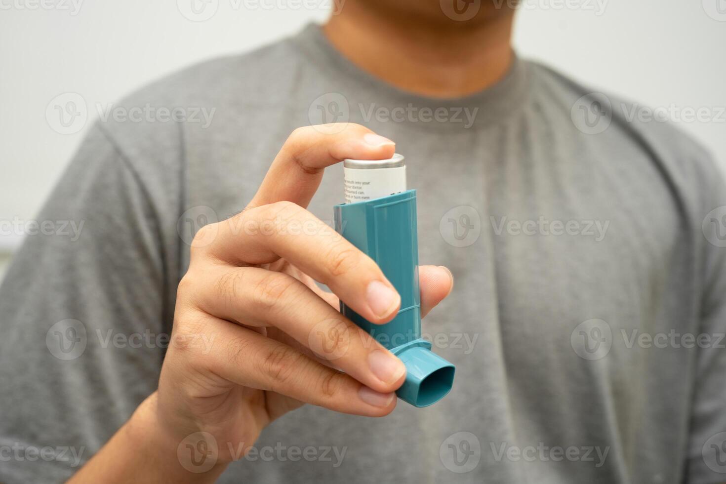 Asthma and chronic obstructive pulmonary disease COPD, Asian young man using metered dose inhaler MDI. photo
