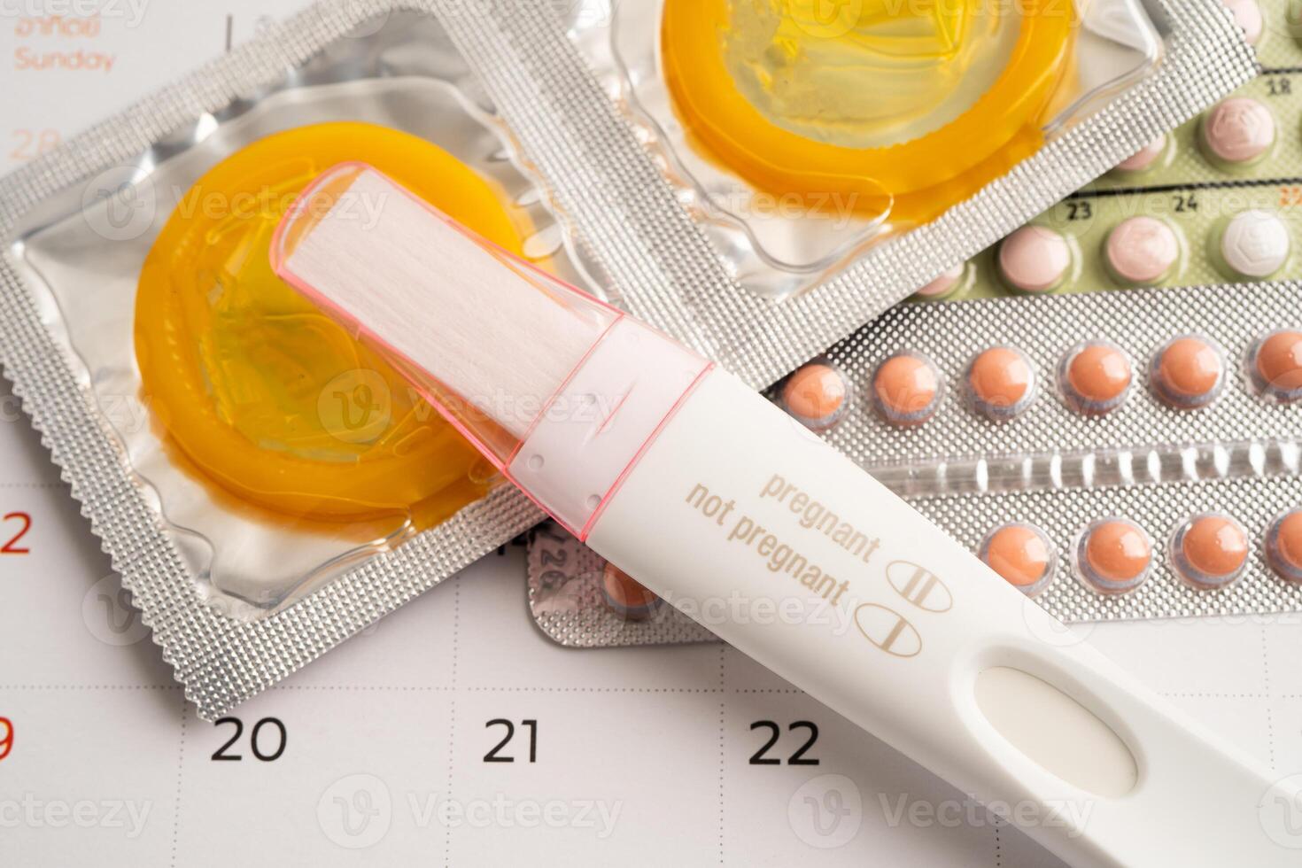 Pregnancy test and birth control pills on calendar, contraception health and medicine. photo