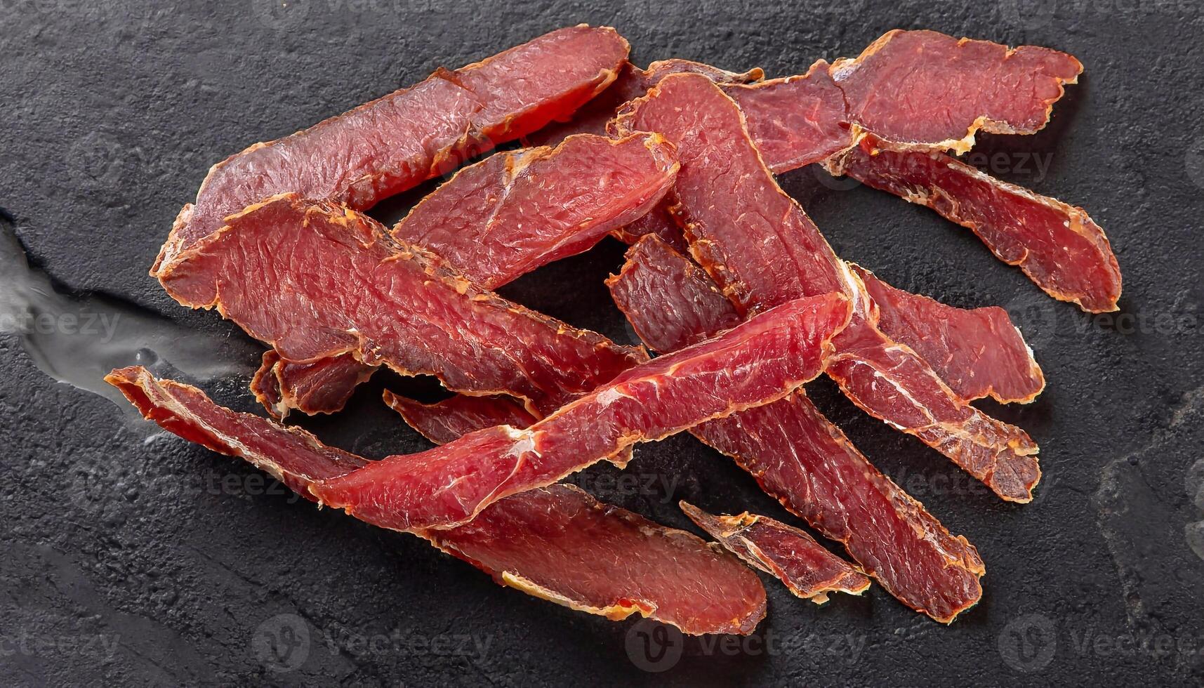 macro photo of dried sliced lamb basturma on black marble surface top view
