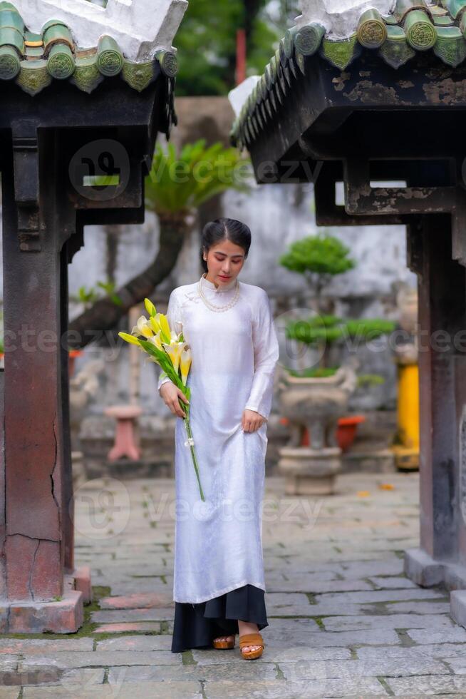 Vietnamese girl with Ao Dai dress standing in temple in Ho Chi Minh city, Vietnam. Ao dai is famous traditional costume for woman in Vietnam photo