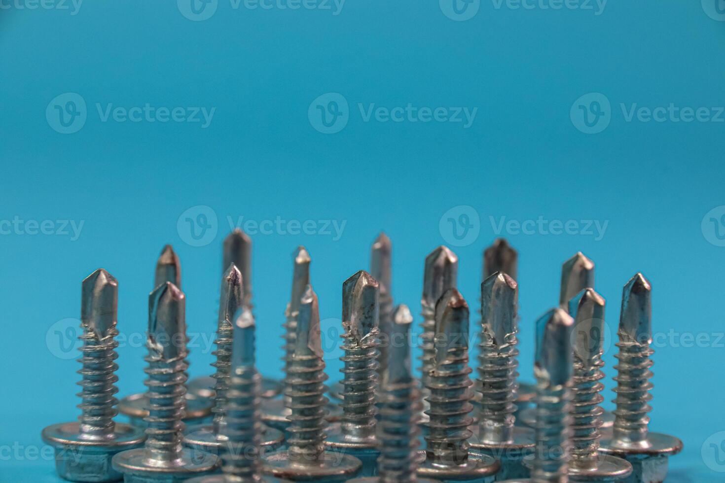 arranged screw rivet on blue background, manufacturing tools concept photo