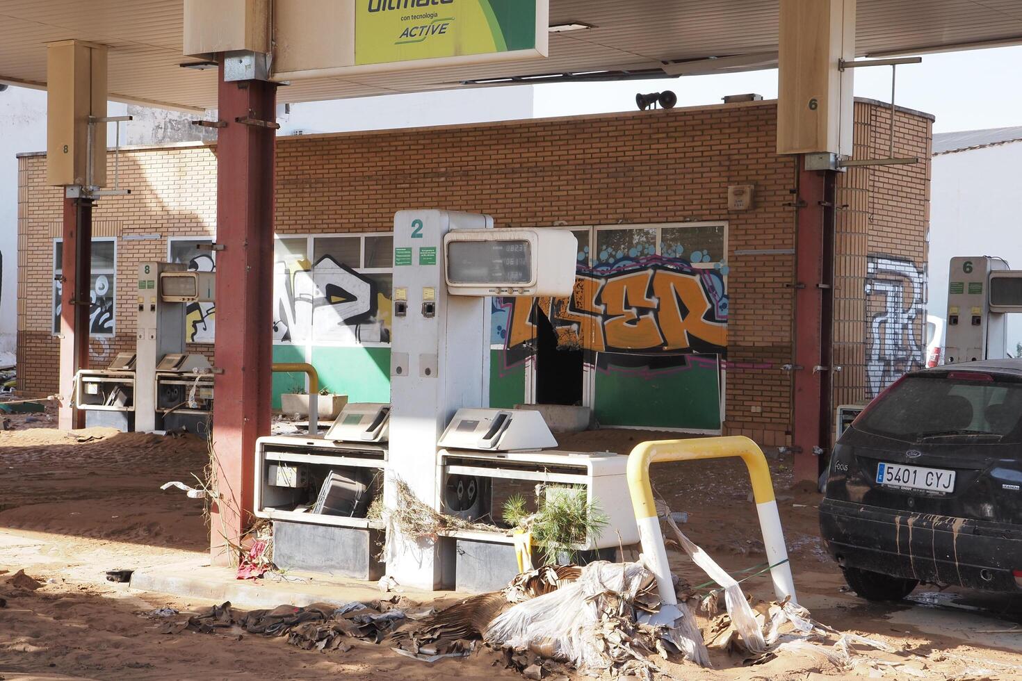 VALENCIA, SPAIN OCTOBER 31, 2024. Muddy gas station showing the devastating consequences of flooding in Valencia, with graffiti and debris covering the area photo