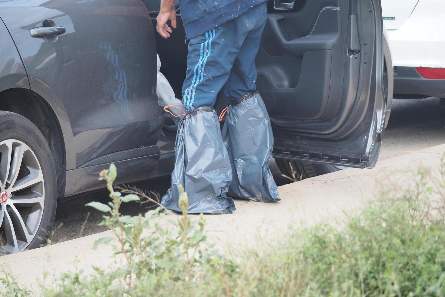 VALENCIA, SPAIN OCTOBER 31, 2024. Worker improvising boots with plastic bags getting out of his car after a flood in Valencia, Spain photo