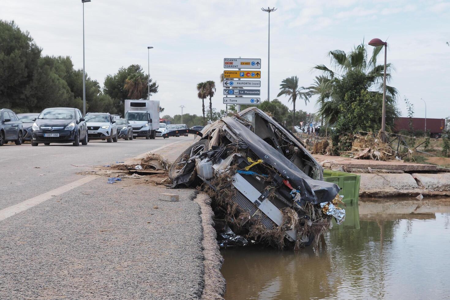 VALENCIA, SPAIN OCTOBER 31, 2024. Devastating consequences of flooding in Valencia, with a destroyed car lying on the roadside photo
