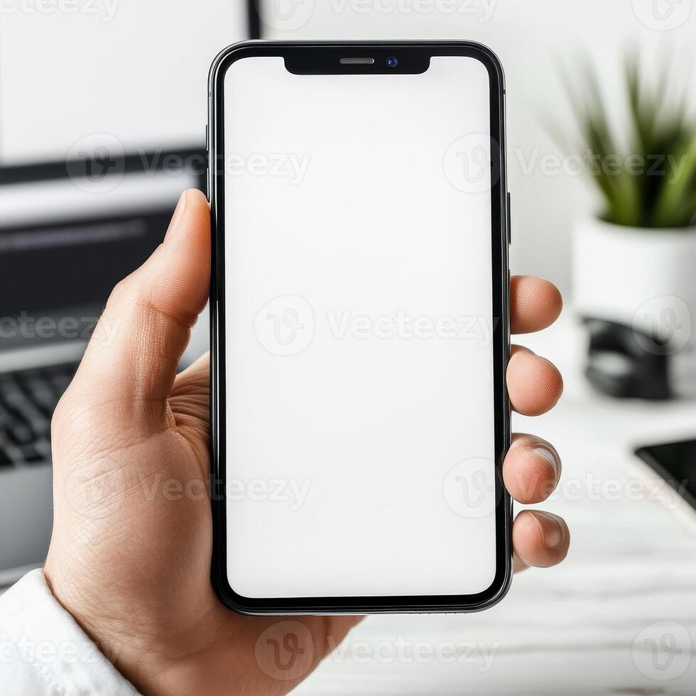 mockup of a blank white cell phone screen. texting while holding a mobile device at an office workstation. background void for advertising. work personnel in contact photo