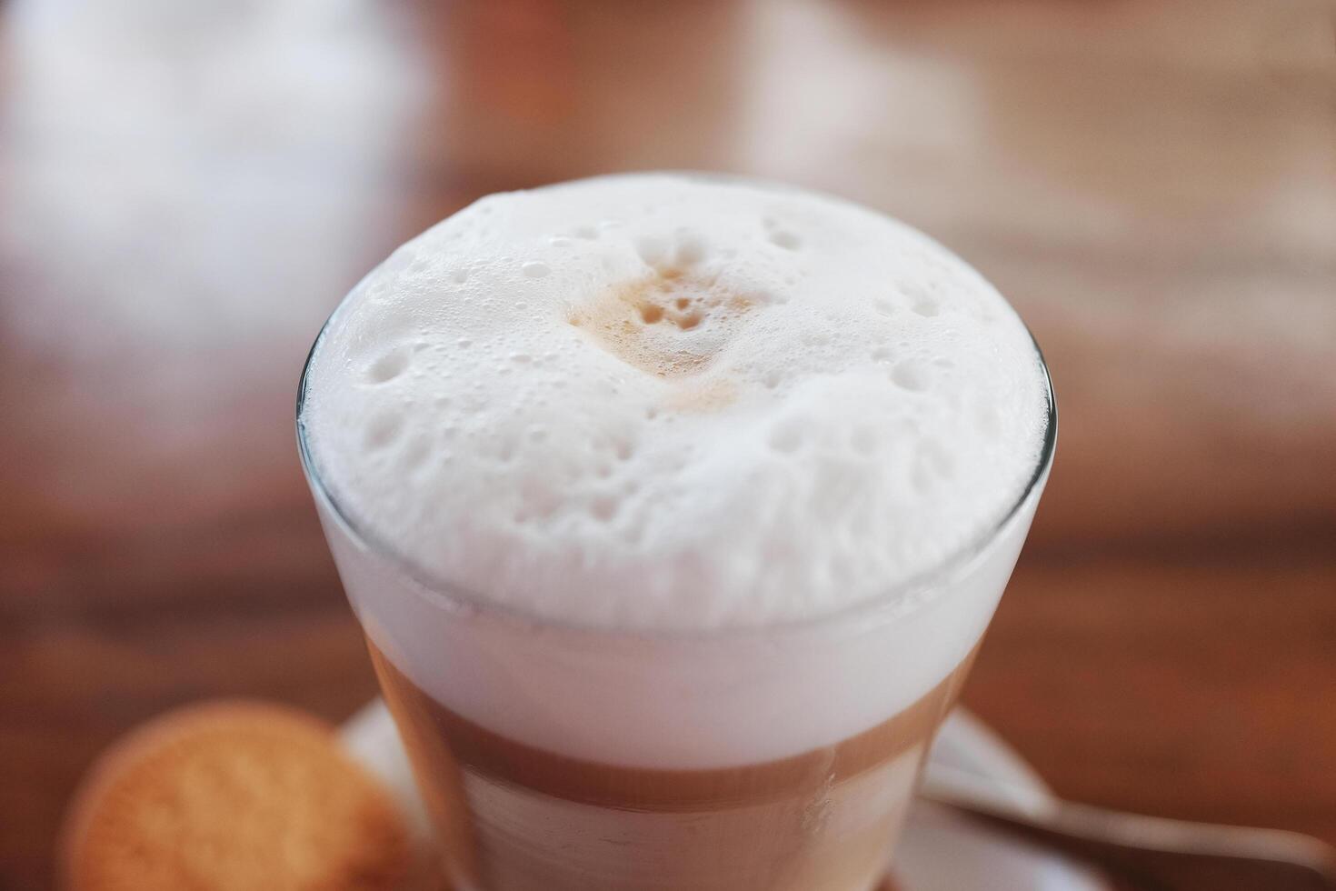 fresh hot latte coffee drink with milk foam on wooden table in cafe photo