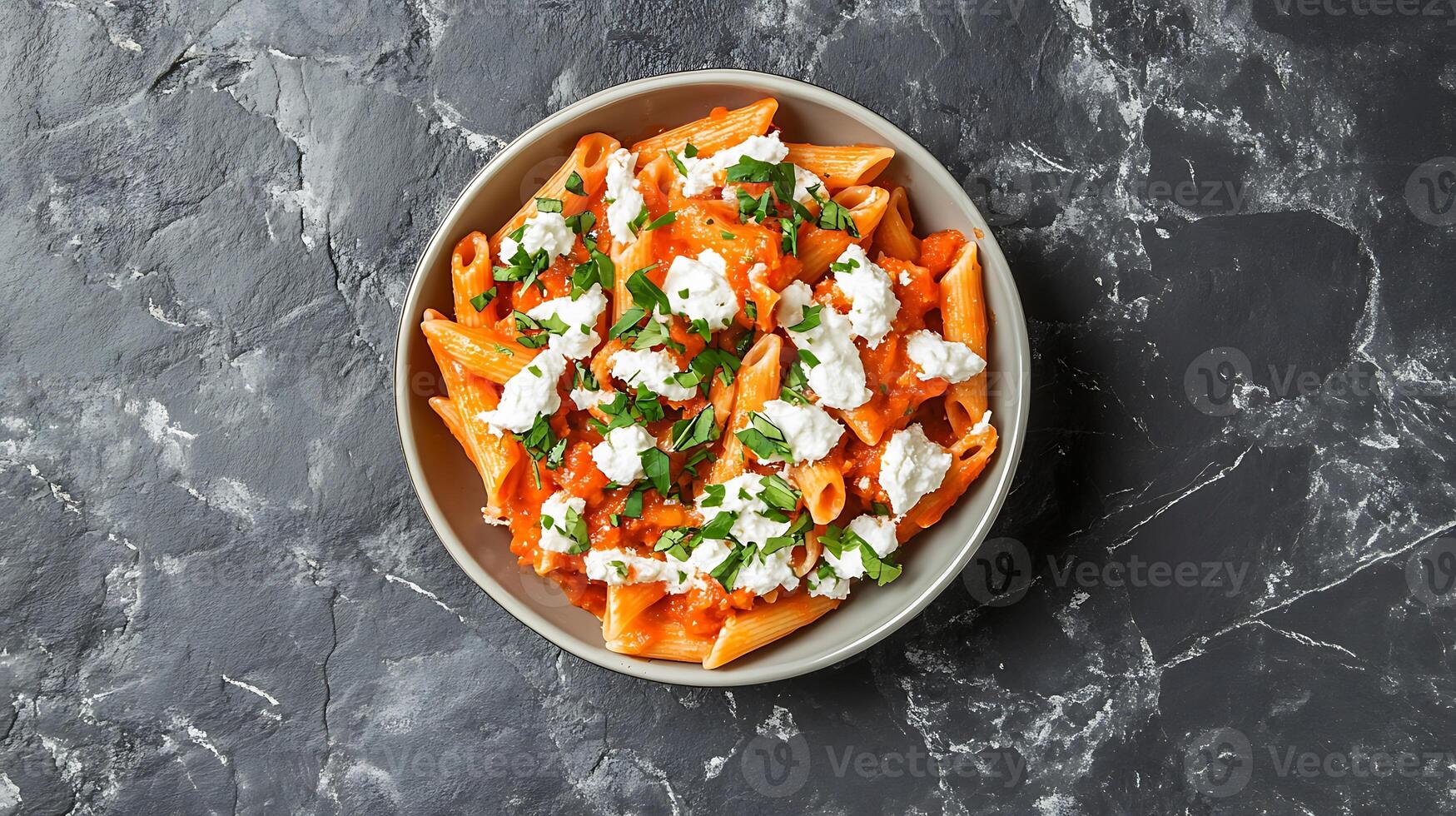 Pasta penne with roasted tomato, sauce, mozzarella cheese. Grey stone background. Top view photo