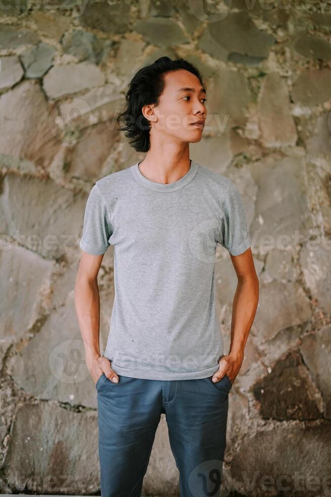 Southeast Asian man standing and looking to the side with a calm expression photo