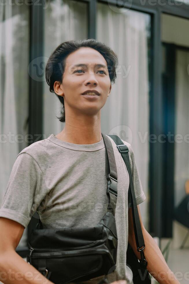 Southeast Asian man standing in front of a house with a relaxed expression photo