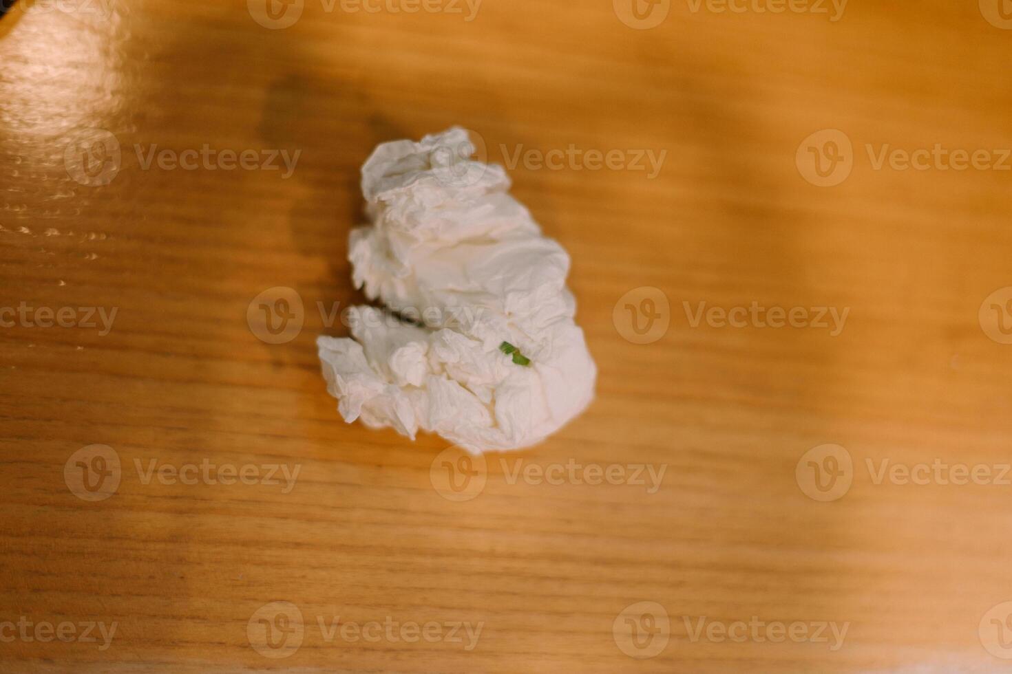 Used tissue paper discarded, crumpled and resting on a plain surface photo