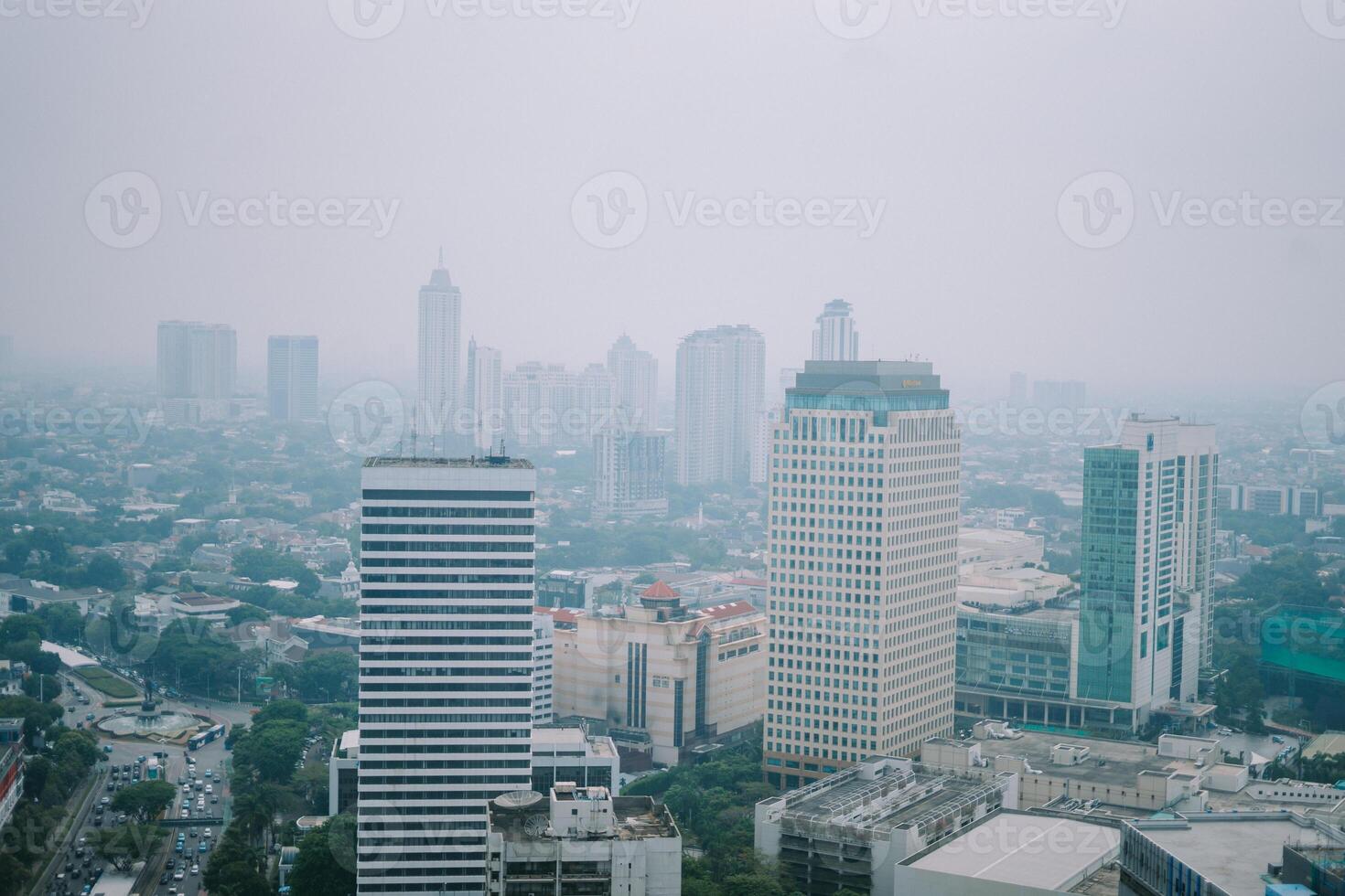 High-rise buildings and a major road in Jakarta city, with visible air pollution creating a hazy urban atmosphere photo