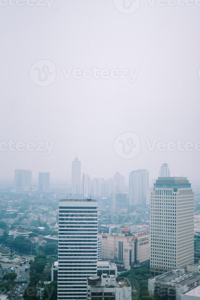 High-rise buildings and a major road in Jakarta city, with visible air pollution creating a hazy urban atmosphere photo