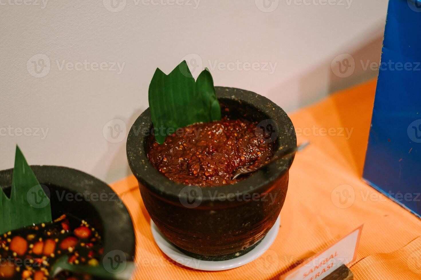 An assortment of traditional sambal varieties in clay bowls, showcasing vibrant colors and rich textures photo