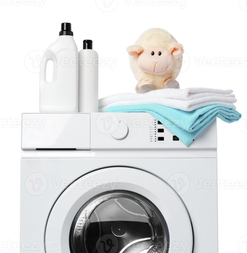 White Laundry Detergent Bottles, Sheep Toy, and Towels on Top of a White Washing Machine photo