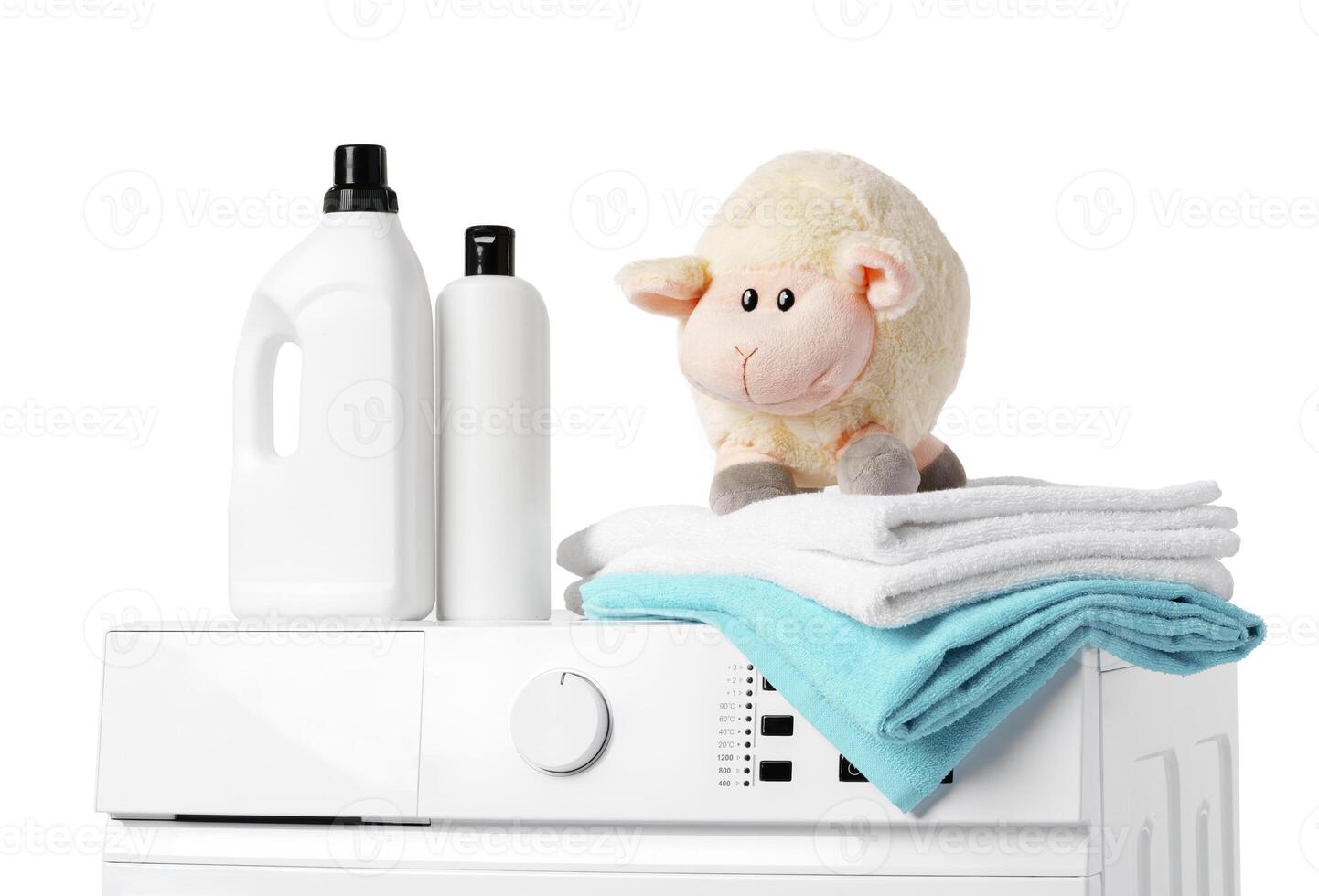 Laundry Detergent Bottles, Sheep Toy, and Towels on Top of a White Washing Machine photo