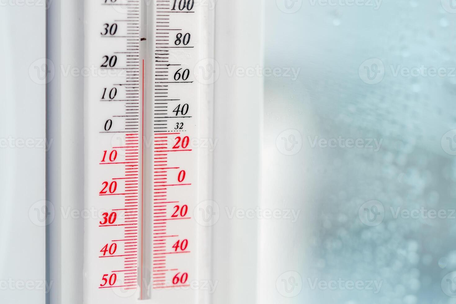 White Plastic Thermometer Attached to a Window With a Plant in the Foreground photo