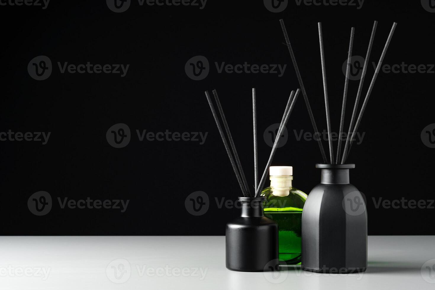 Two Black Reed Diffuser Bottles on a White Surface With Grey Background photo