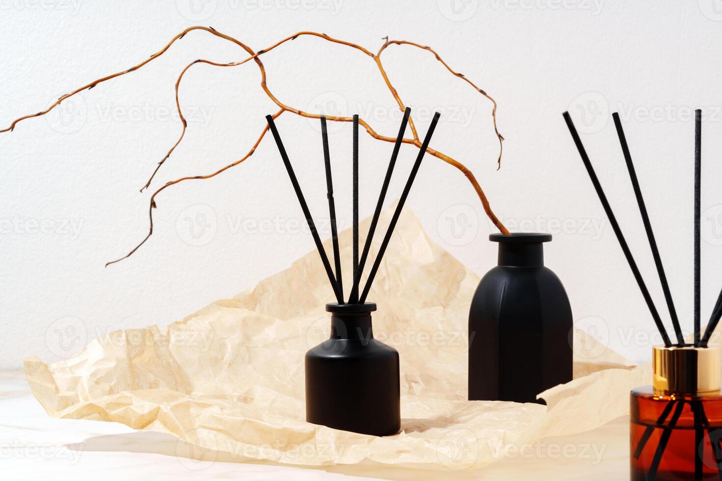 Black Glass Diffuser Bottles With Reed Sticks and Dried Twigs on Cream Paper photo