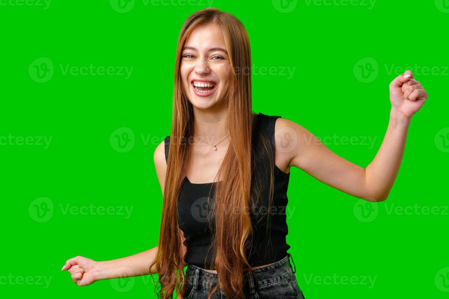 Young Woman With Long Brown Hair Laughing and Dancing in Front of Green Screen photo