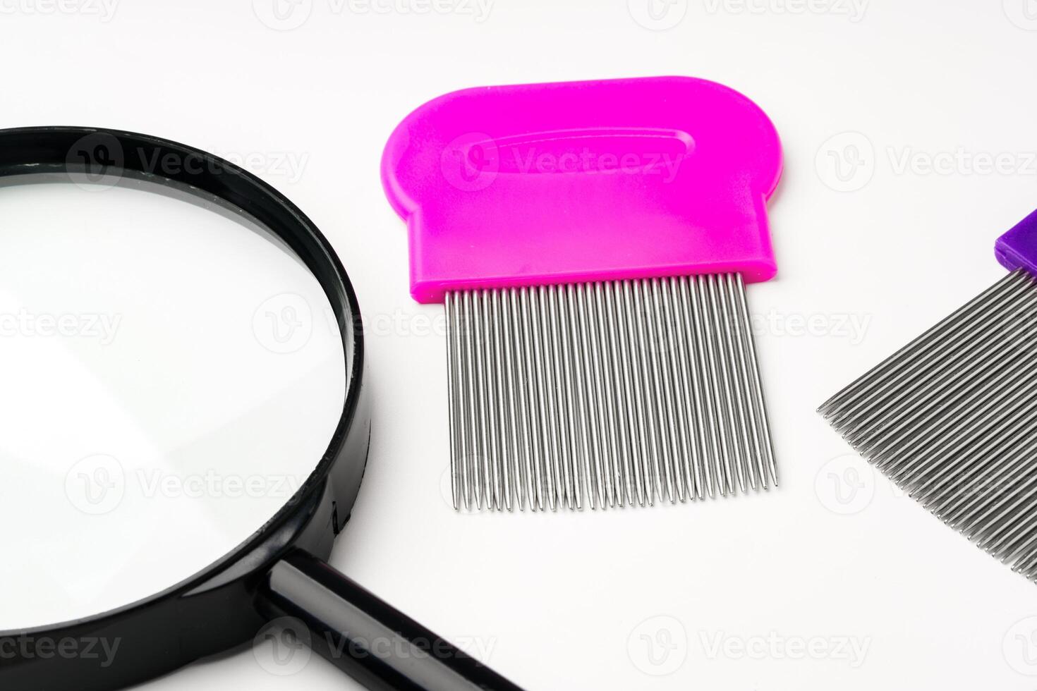 A magnifying glass and lice comb placed side by side on a clean white background photo