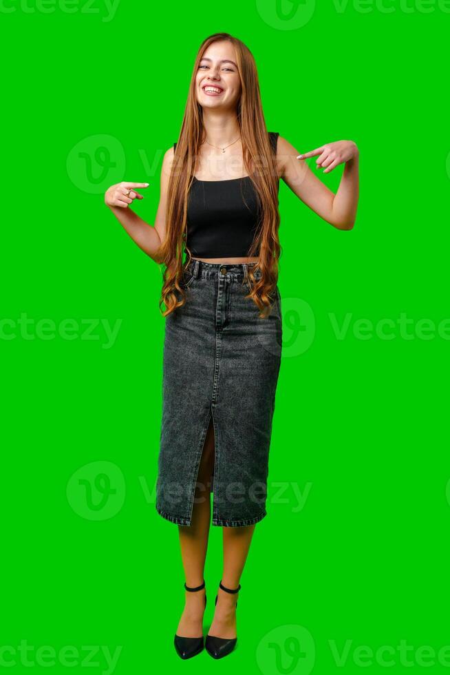 Young Woman Smiling and Pointing at Herself in Front of a Green Screen photo