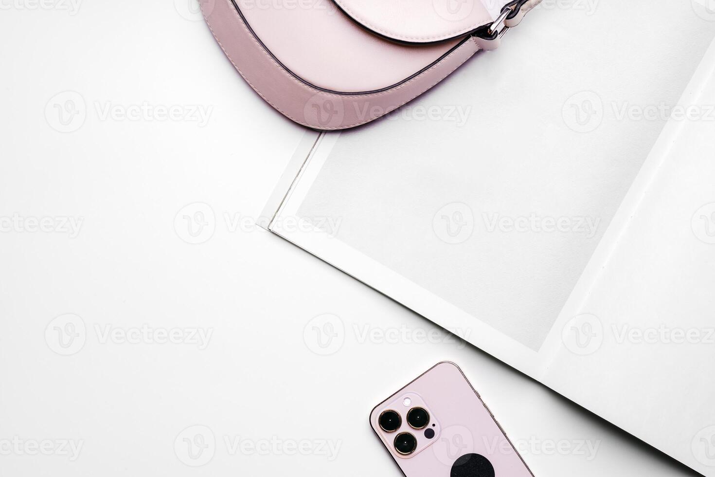 Open notepad with smartphone and female bag on white background photo