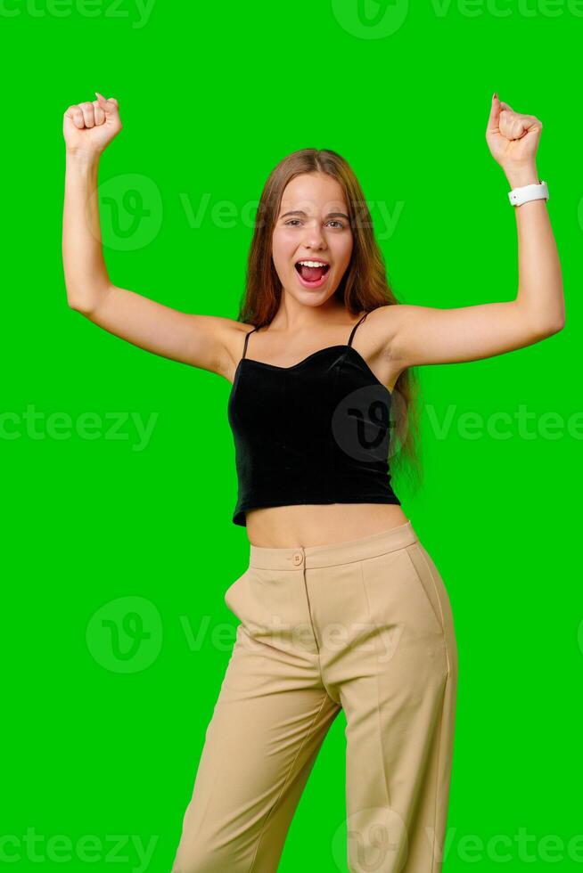 Young Woman Celebrating Success With Raised Fists Against Green Screen Background photo