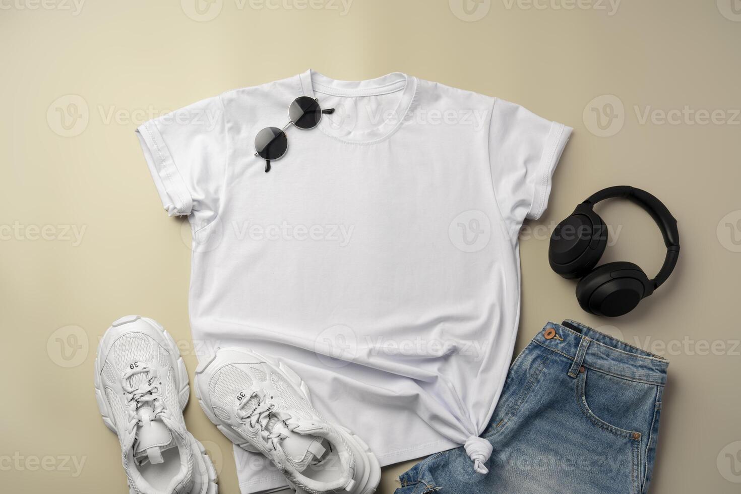 White T-shirt, jeans and sneakers on beige background photo