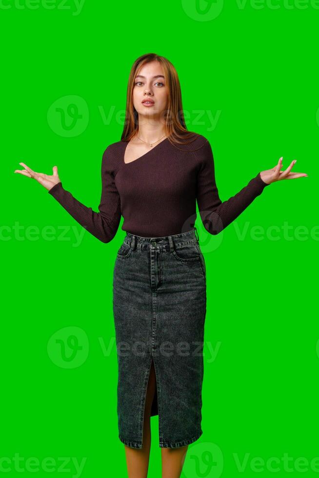Young Woman Gesturing With Open Palms in Front of Green Screen photo