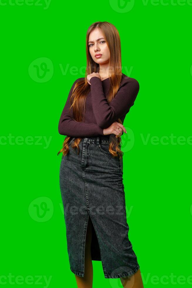 Young Woman Posing With Arms Crossed Against Green Screen photo