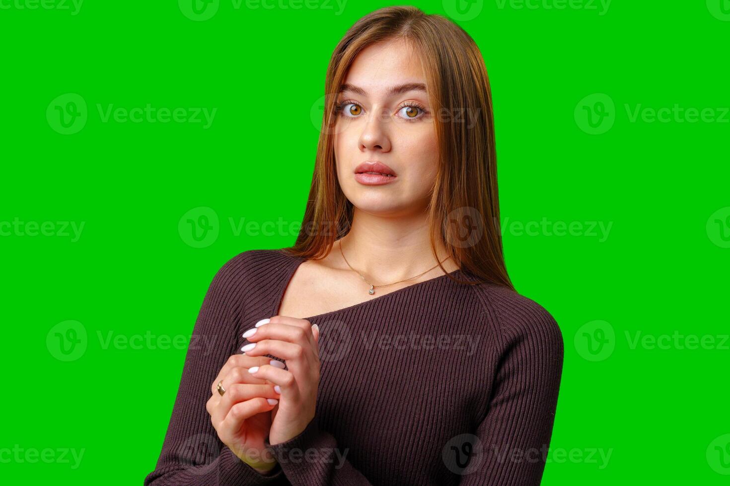 Young Woman in Brown Sweater Posing Against Green Screen photo