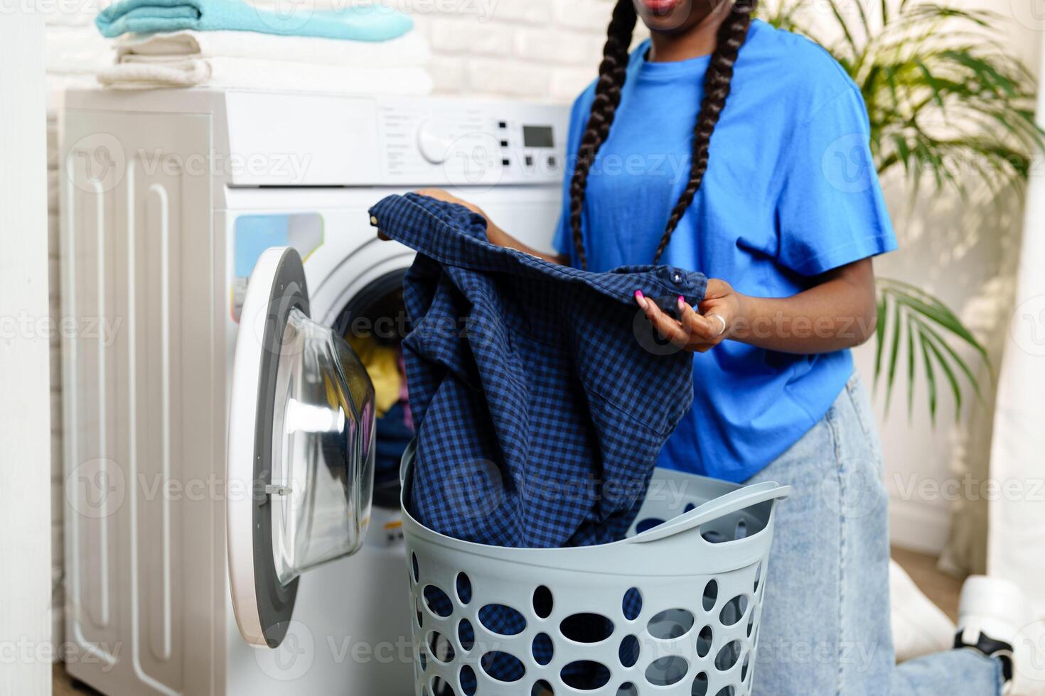 African Woman Loading Laundry Into Washing Machine in Home photo