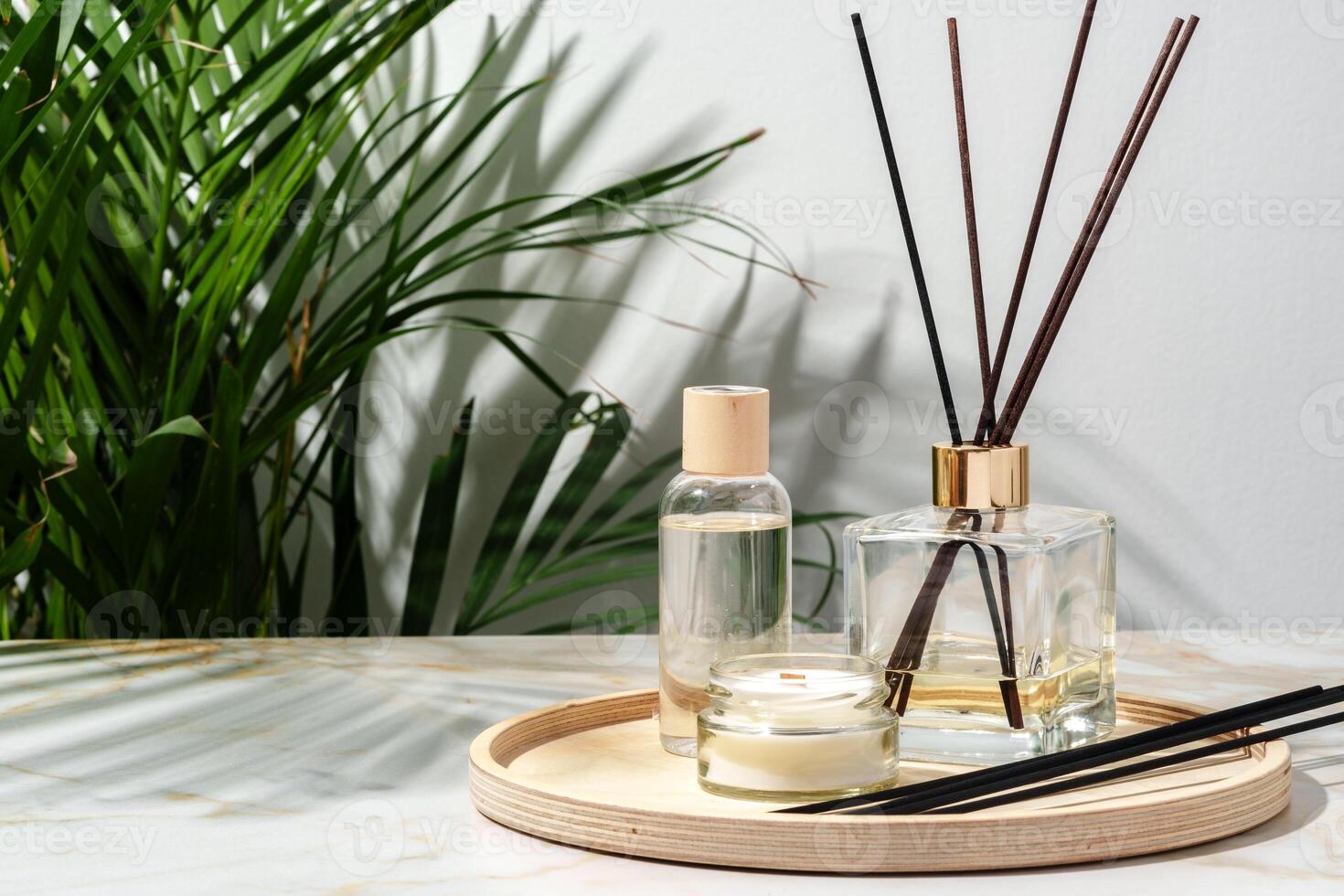 Black Reed Diffuser, Amber Candle, and Wooden Tray on White Surface photo