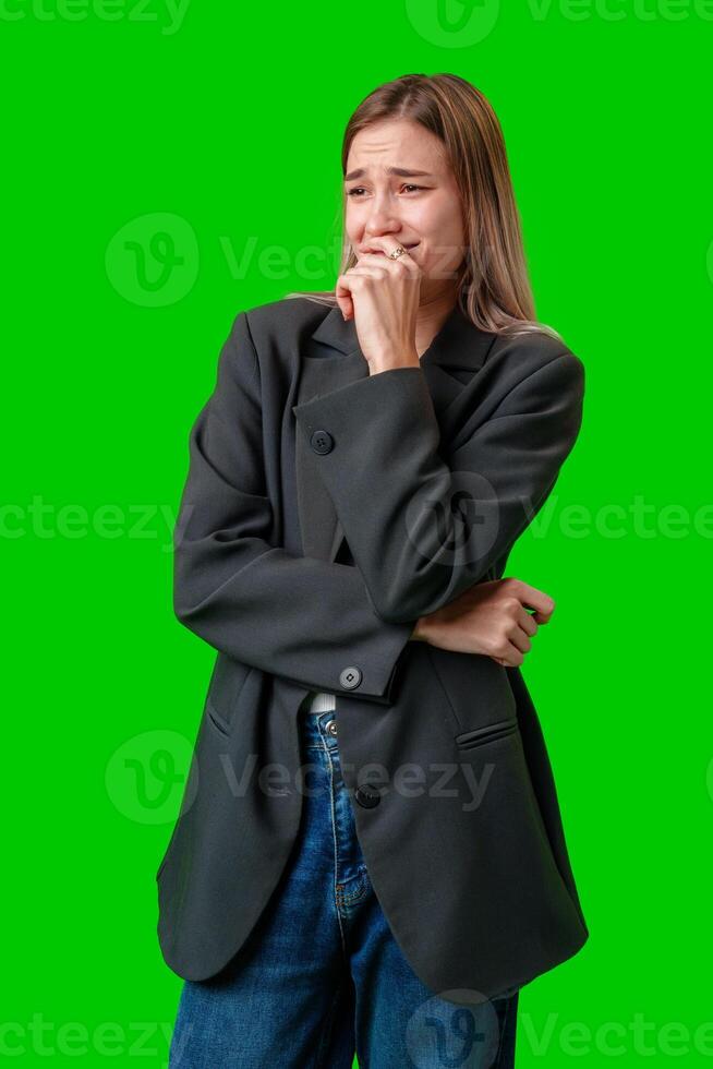 Young Woman Crying While Wearing a Black Blazer Against a Green Screen photo