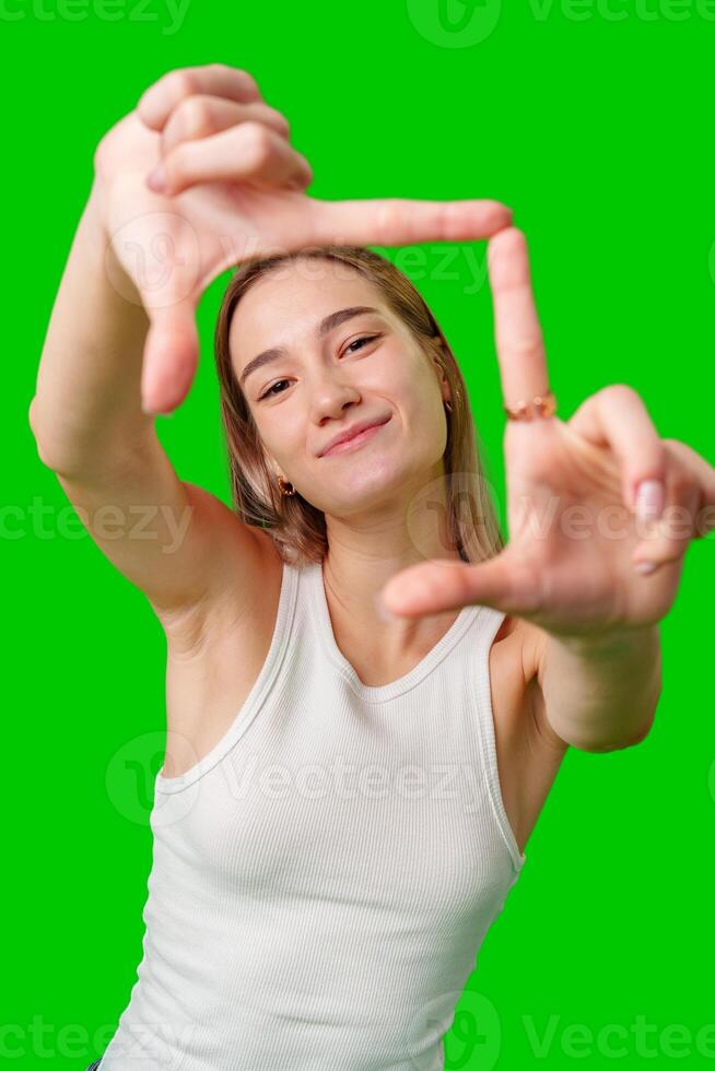 Young Woman Framing With Fingers Against Green Screen photo