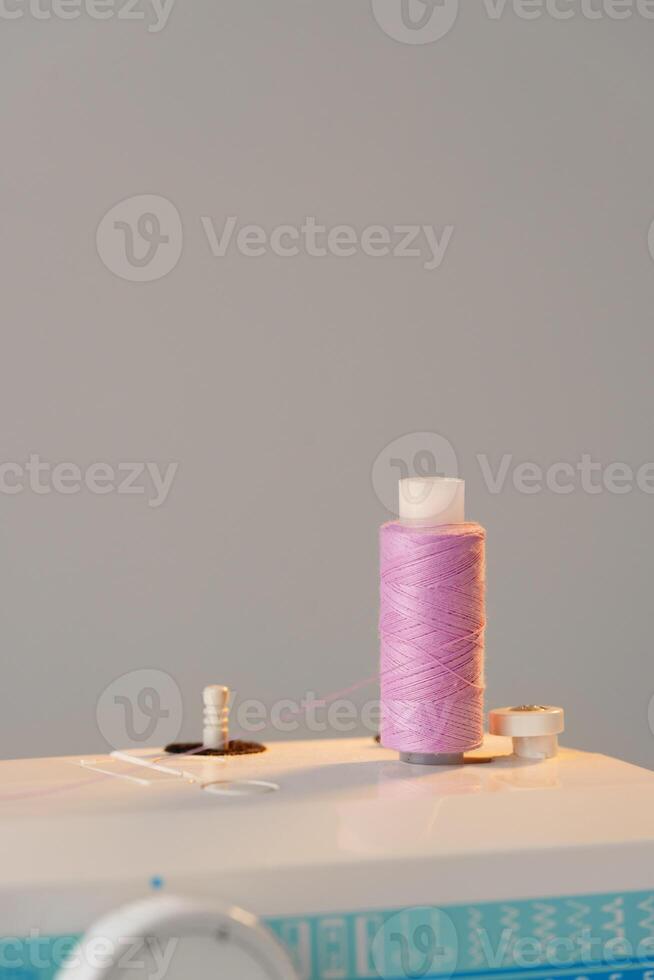 View of a sewing machine with a spool of pink thread placed on top photo