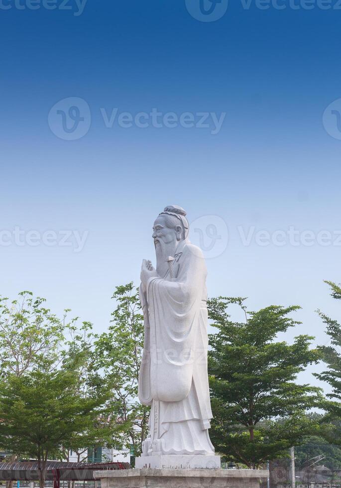 Confucius sculpture Located in the middle of tall green trees photo