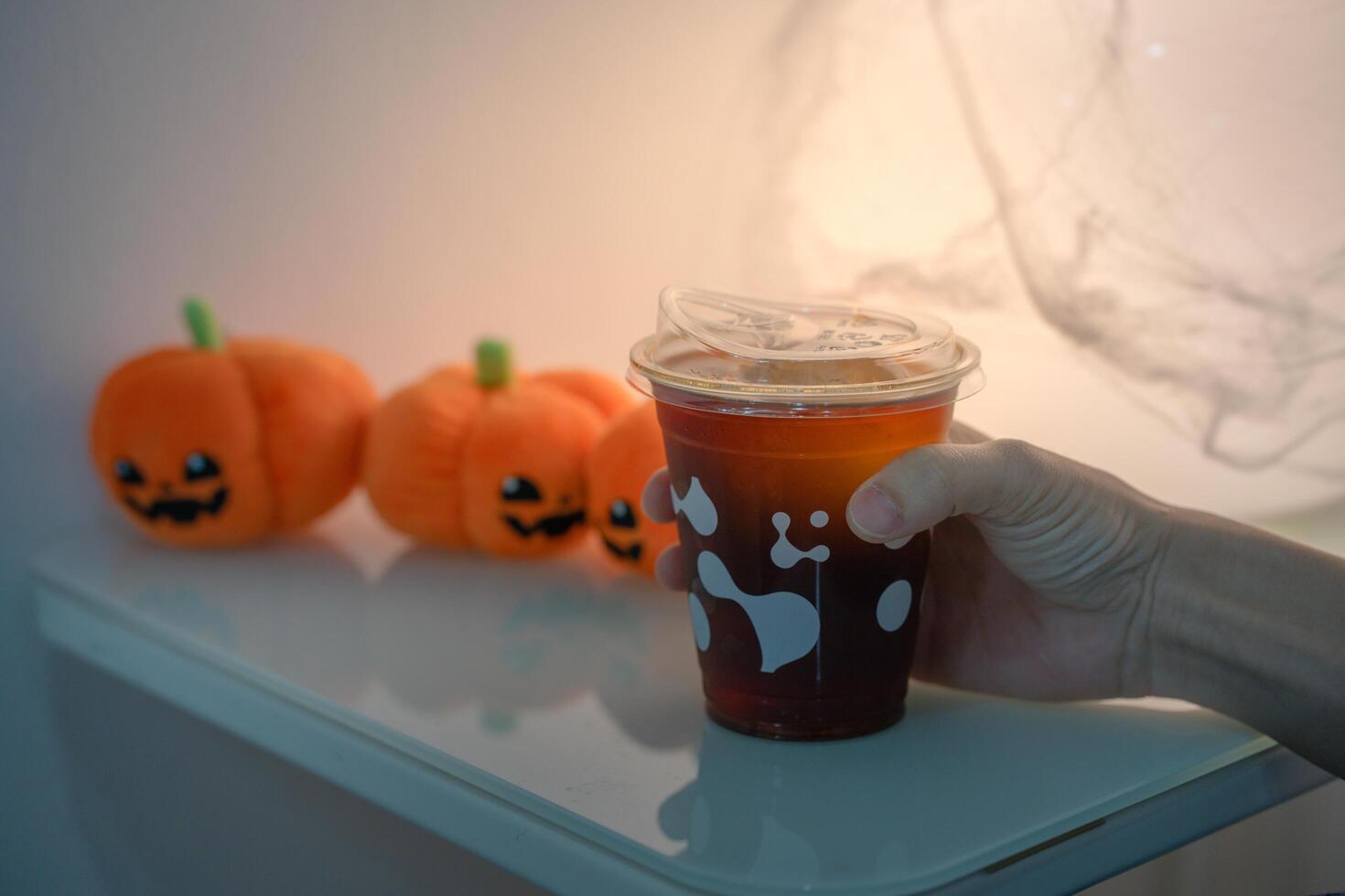 hand holding halloween drink black coffee in glass on table. Selective focus photo